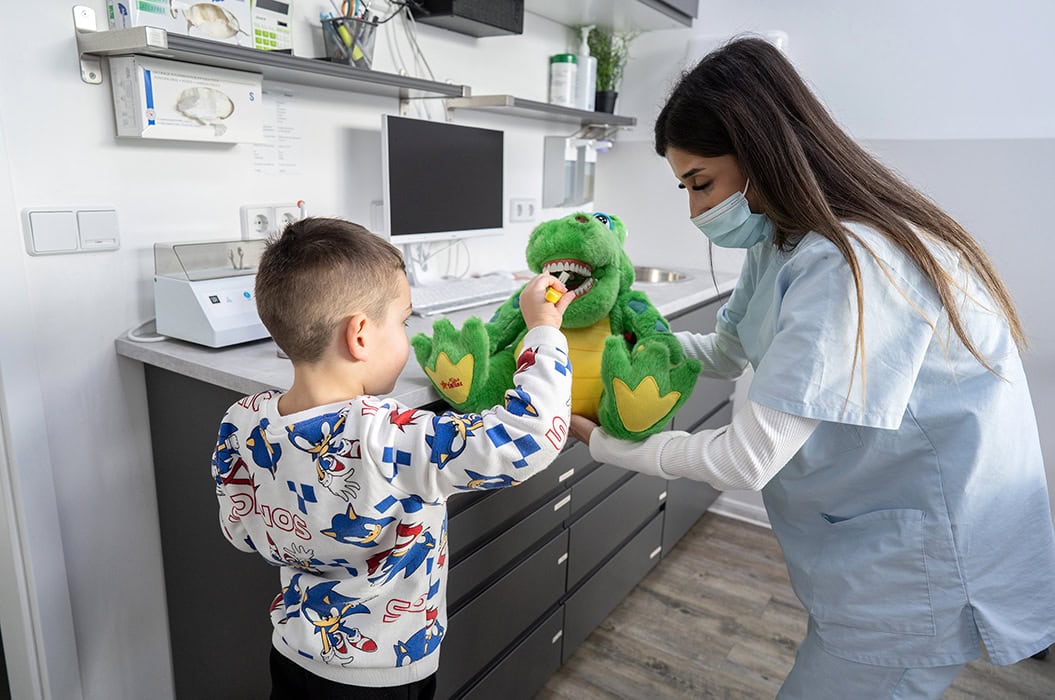 Kinderzahnärztin spielt mit einem Kind und Dino Stofftier in Berlin Neukölln