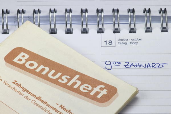 Bonusheft auf einem Kalender mit der Notiz Zahnarzt-Termin