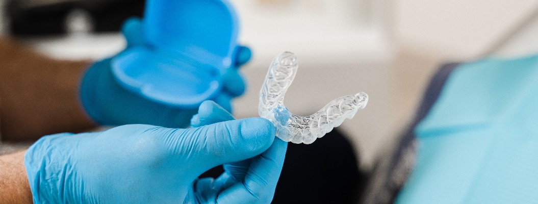 Transparenter Aligner für Bisskorrektur und Zahnformung in Großaufnahme. Kieferorthopäde zeigt transparenten herausnehmbaren Retainer für eine Patientin in der Zahnmedizin.