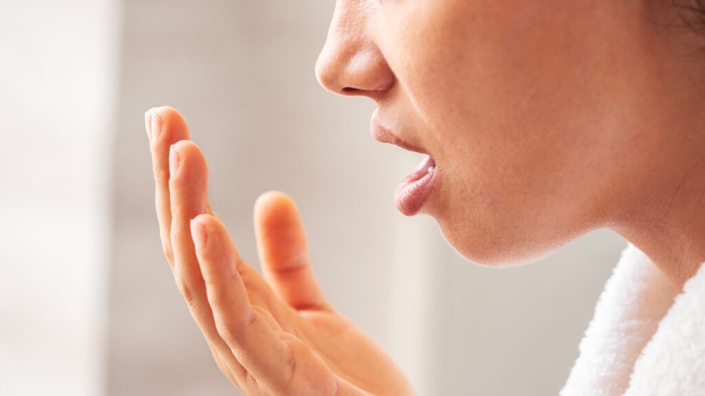 Woman is checking smell of breath