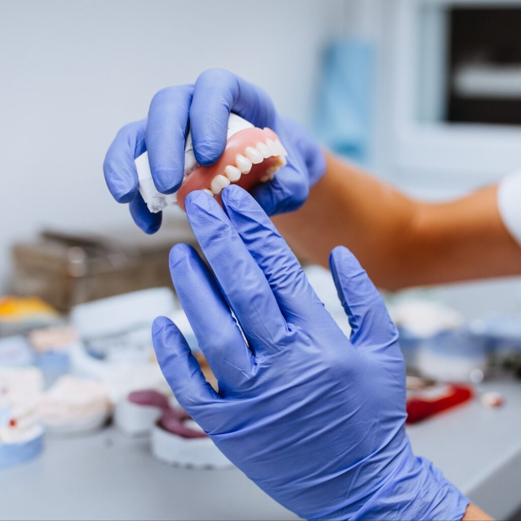 Nahaufnahme der Hände des Zahntechnikers bei der Arbeit an der Zahnprothese in Buckow